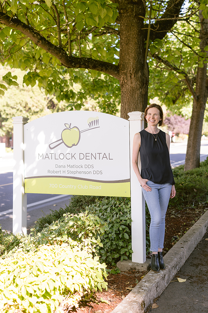 Dr. Matlock standing in front of her dentist practice's sign, Matlock Dental in Eugene, Oregon.