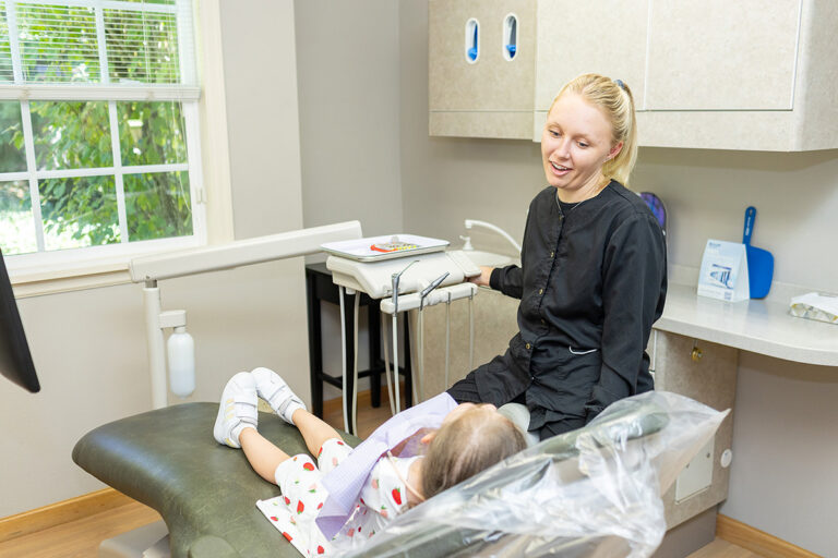 Mikayla laughing with a small child patient at Matlock Dental in Eugene, Oregon.